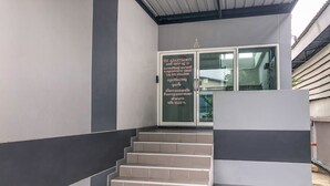 A staircase leading to a door with a sign, a modern building facade, and a metal roof. - K&k Apartment (Bang Phli)
