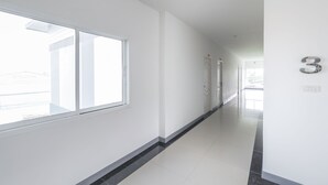 A bright, modern hallway with white walls and a large window on the left. - K&k Apartment (Bang Phli)