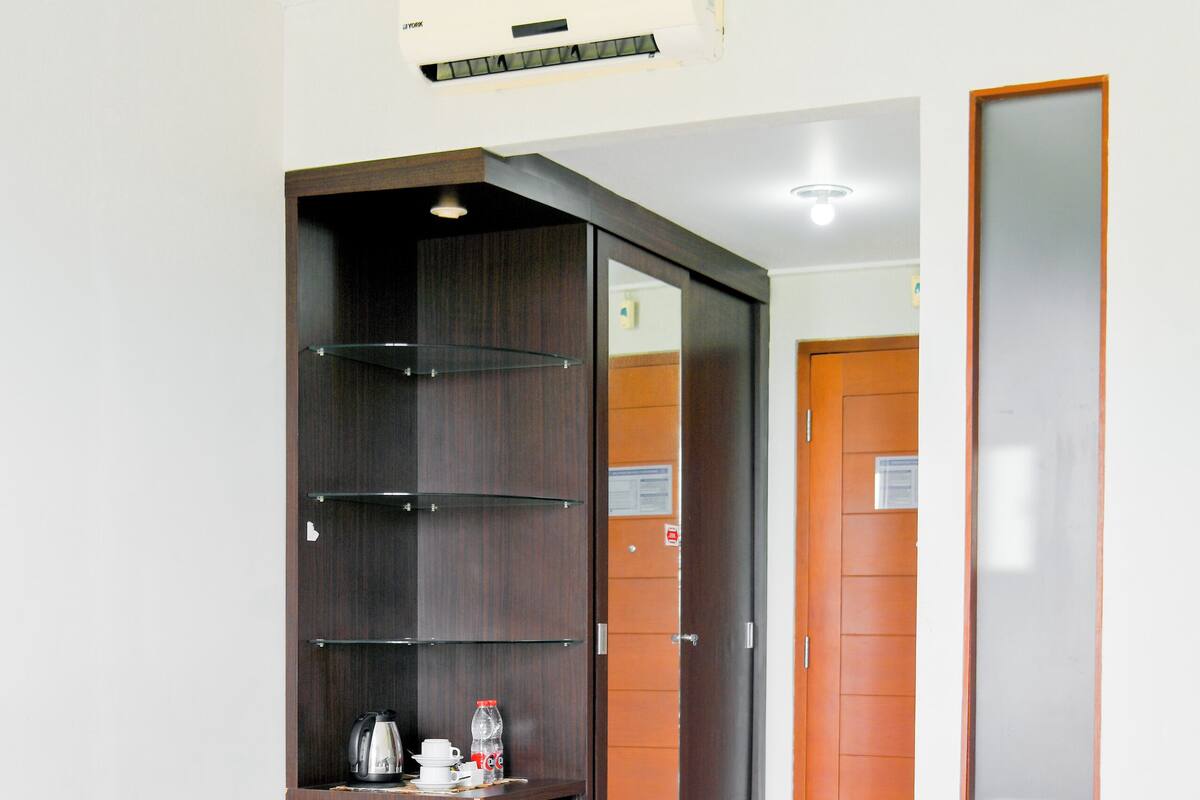 A hotel room with a bed, a desk, a wardrobe, and a mini-fridge.