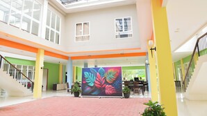 A spacious atrium with a high ceiling, large windows, and a central colorful artwork.
