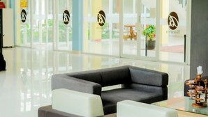 A modern lobby with a grey sofa, a coffee table, and a glass partition.
