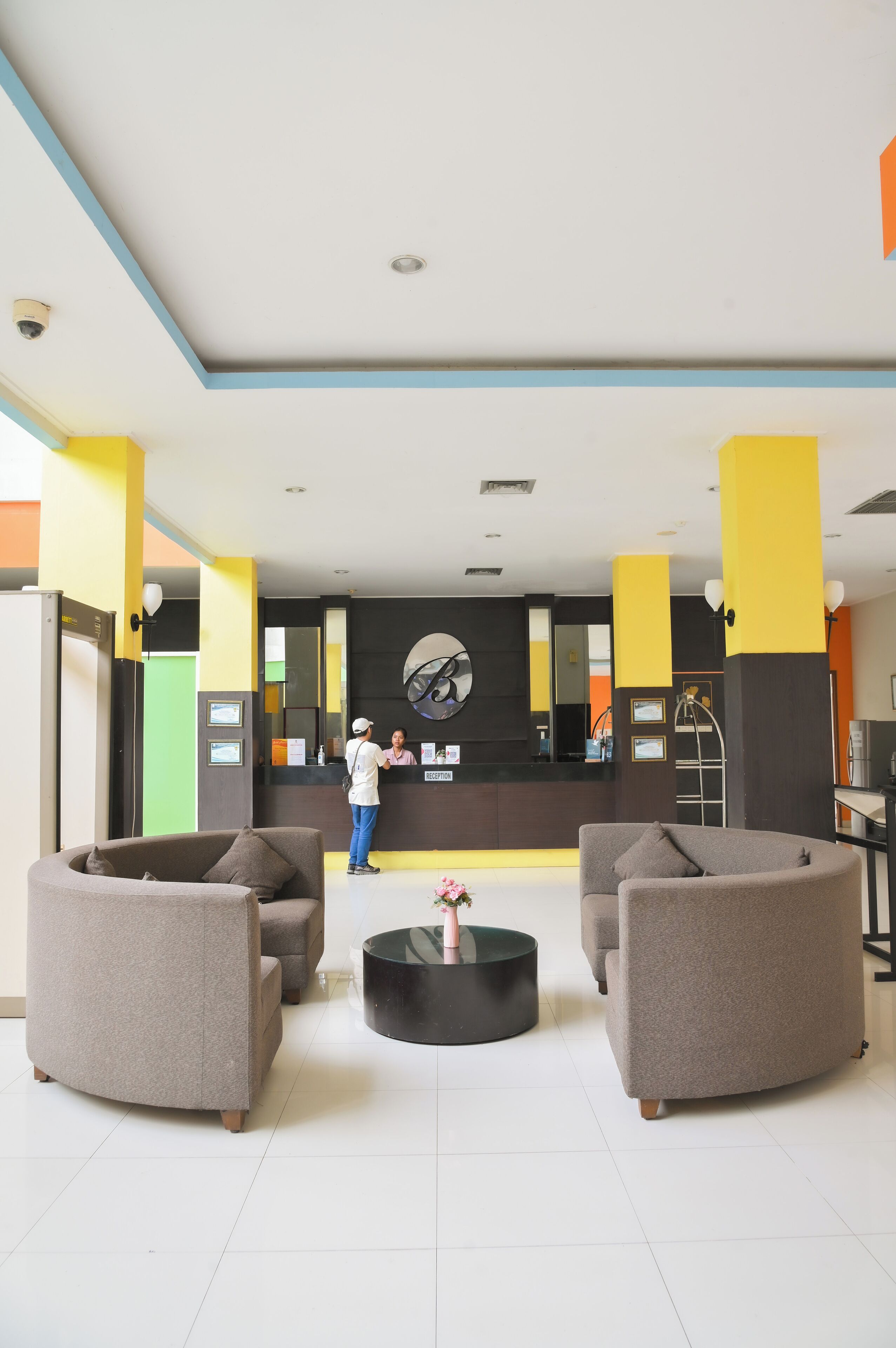 A lobby with two sofas, a reception desk, and a large mirror.