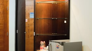 A compact room with a sliding door, a small table with a bottle, and a refrigerator.
