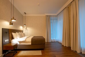 A modern hotel room with a large bed, bedside tables, and hanging pendant lights. - Botanica Hotel (Arkhangelsk)