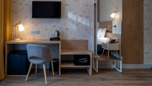 A modern hotel room with a wooden desk, a chair, a television, a mirror, and a wardrobe. - Botanica Hotel (Arkhangelsk)