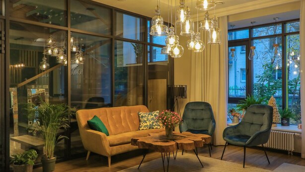 A modern living room with a sofa, armchairs, and a coffee table. There are large windows with a view of the city. - Botanica Hotel (Arkhangelsk)