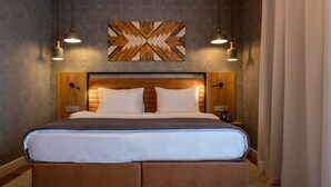 A large bed with a wooden headboard, two bedside tables, and a wall-mounted artwork above. - Botanica Hotel (Arkhangelsk)
