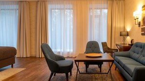 A modern living room with a sofa, two armchairs, a coffee table, and a dining table. - Botanica Hotel (Arkhangelsk)