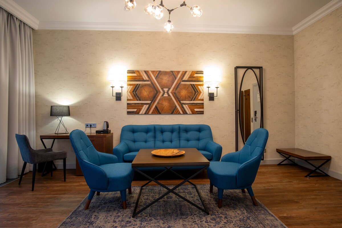 A modern living room with a blue sofa set, a wooden coffee table, and a patterned rug.