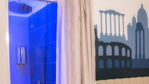 A bathroom with a blue-tiled shower area, a beige curtain, and a wall mural depicting ancient architecture. - Frattina FF (Rome)