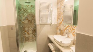 A bathroom with a glass-enclosed shower, a white sink, and patterned tiles. - Frattina FF (Rome)