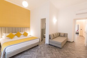 Una habitación de hotel con una cama, un sofá y un suelo con estampado tipo espiga.
