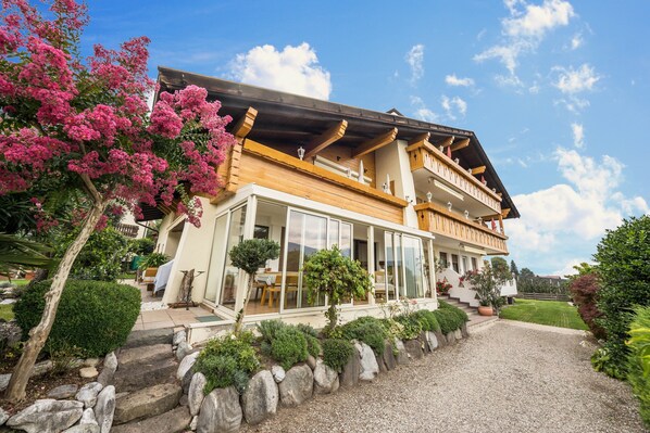 A two-story house with a balcony, a stone pathway, and a garden.