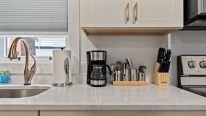 Eine Küche mit Spüle aus Edelstahl, einer Kaffeemaschine und einem Messerblock.