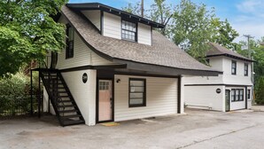Ein zweistöckiges Haus mit Garage, Treppe und einer kleinen Veranda.