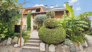 Una casa con un sendero de piedra que conduce a la entrada, rodeada de plantas y rocas.