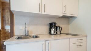 Una cocina con un lavamanos, una cafetera y armarios.