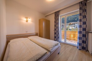 A bedroom with a bed, a wardrobe, a wall-mounted light, and a sliding glass door leading to a balcony.