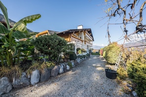 A pathway leading to a wooden house with a balcony, surrounded by rocks and plants.