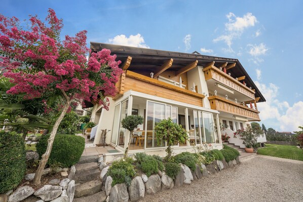 A two-story chalet with a balcony, a covered porch, and a well-maintained garden.