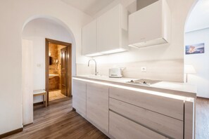 A modern bathroom with a shower, a sink, and a toilet. There is a wooden bench in the shower area.