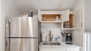 Una cocina moderna con refrigerador de acero inoxidable, pileta integrada y muebles de cocina blancos.