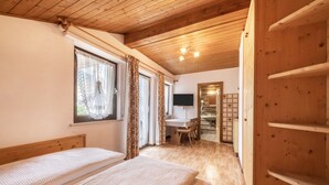 Een slaapkamer met twee bedden, een bureau, een stoel, een televisie en een houten plafond.