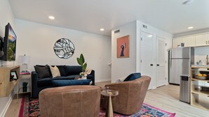 A modern living room with a sofa, two armchairs, a coffee table, and a colorful rug.
