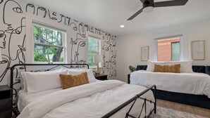 A bedroom with two beds, a ceiling fan, and a window with a view of trees.