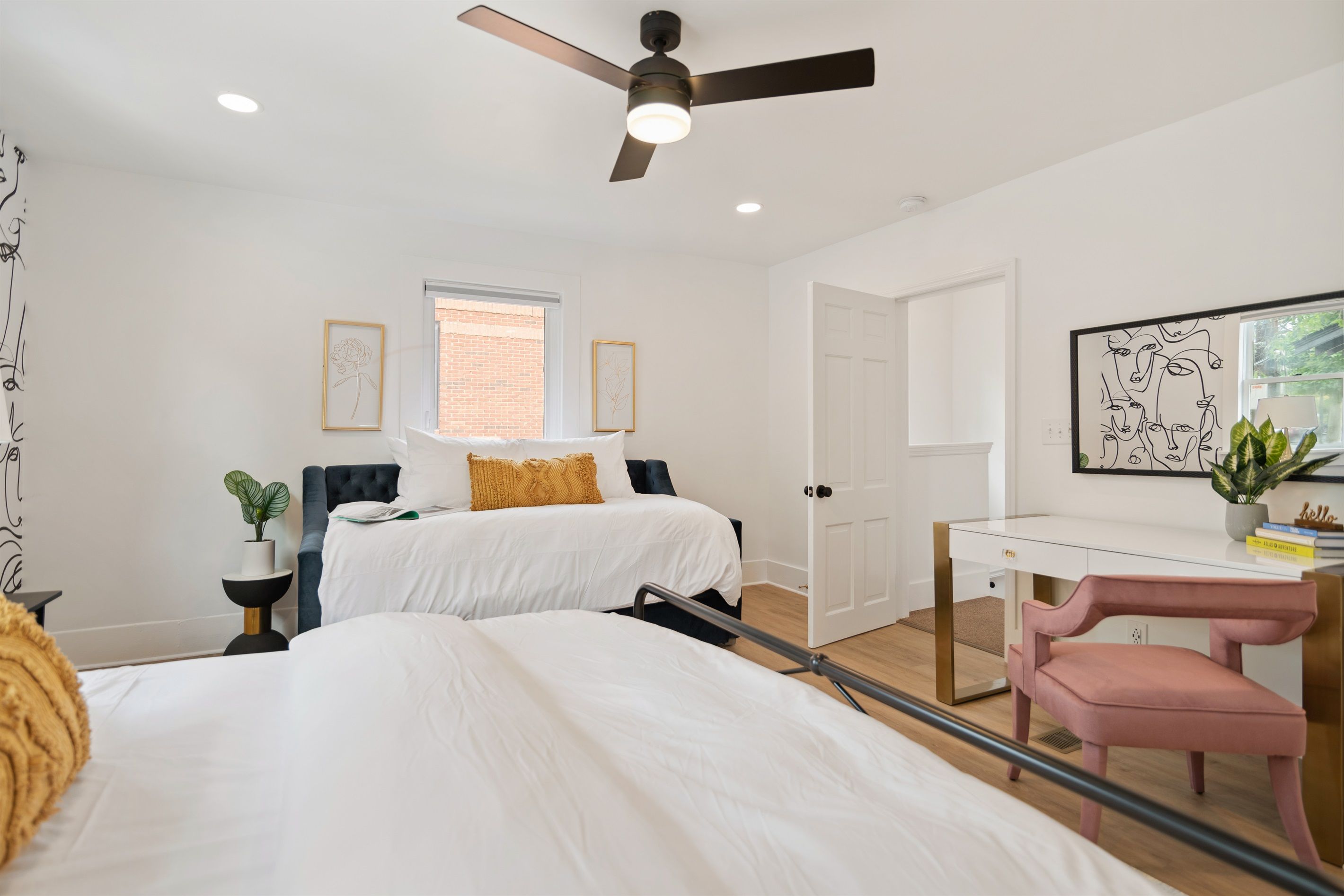 A modern bedroom with two beds, a desk, and a chair.