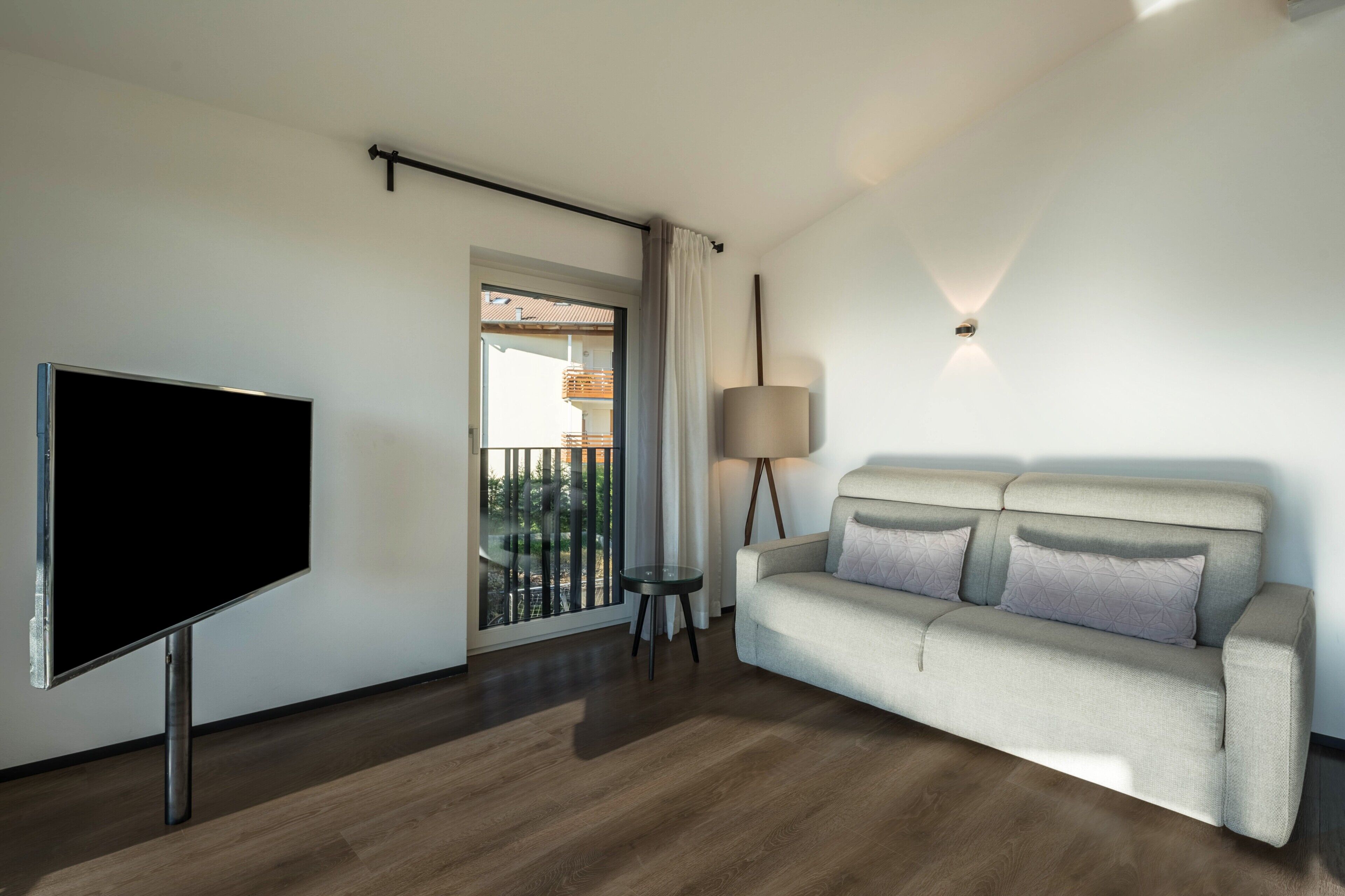 Un salon moderne doté d’un téléviseur à écran plat, d’un canapé, d’une lampe et d’un balcon offrant une vue agréable.