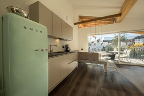 A modern kitchen with a vintage-style refrigerator, wooden beams, and a balcony with outdoor seating.