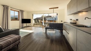 A modern living room with a sofa, a television, and a dining area with chairs and a table.