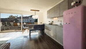 A modern kitchen with a pink refrigerator, a dining area with a table and chairs, and a large sliding glass door leading to an outdoor patio.