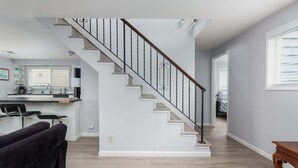 A modern living room with a staircase, a kitchen area, and a dining space. - #155 Nestucca Sunrise · Riverfront, Close to Ocean Beaches, Large Yard (Pacific CIty)