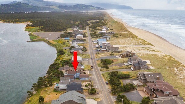 Vista aérea de una zona residencial costera con casas a lo largo de la playa, una carretera y una masa de agua.