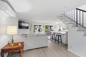 Une cuisine moderne dotée d’un îlot central, d’un coin repas avec un canapé et d’un escalier menant à un niveau supérieur.