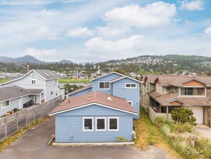 A residential area with houses, a clear sky, and distant hills. - #155 Nestucca Sunrise · Riverfront, Close to Ocean Beaches, Large Yard (Pacific CIty)