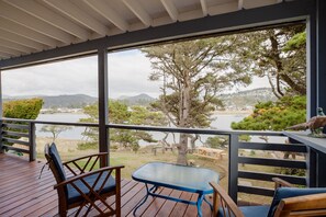 A covered outdoor deck with a view of a lake and hills.