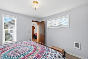 Een slaapkamer met een groot bed, een deur naar een andere kamer en een plafondlamp.