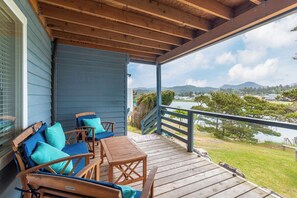 A covered porch with wooden furniture and a view of a lake and mountains.