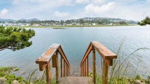 Un muelle de madera que se adentra en un lago tranquilo, con vista a un pequeño pueblo en la distancia.