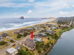 An aerial view of a coastal residential area with houses, a road, and a body of water. - #155 Nestucca Sunrise · Riverfront, Close to Ocean Beaches, Large Yard (Pacific CIty)