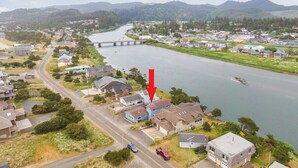 Un barrio residencial con casas a lo largo de un río, un puente y una carretera.