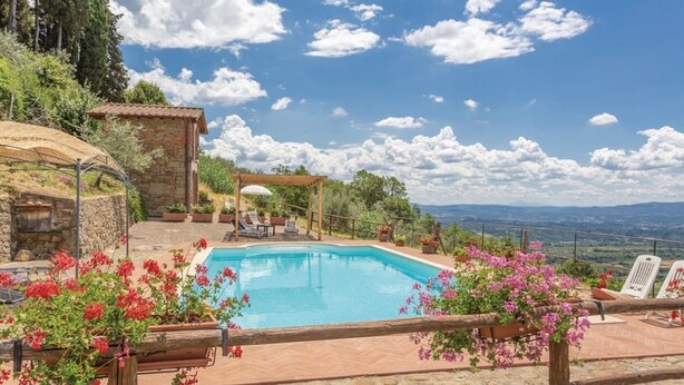 Ein Pool mit einer Steindeck, umgeben von Topfpflanzen und einer Holzpergola.