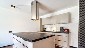 Una cocina moderna con una isla central, muebles blancos y un horno empotrado.
