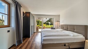 Un dormitorio con una cama grande, una ventana y vista a un jardín.