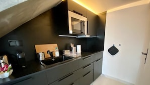 Une cuisine moderne avec des meubles de couleur sombre, un évier en acier inoxydable et un four à micro-ondes.