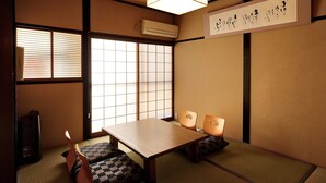 A traditional Japanese room with tatami flooring, a low table, and cushions. - Connect inn Gionbishamoncho (Kyoto)