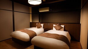 A hotel room with two beds, wooden headboards, a nightstand, and a wall-mounted air conditioner. - Connect inn Gionbishamoncho (Kyoto)